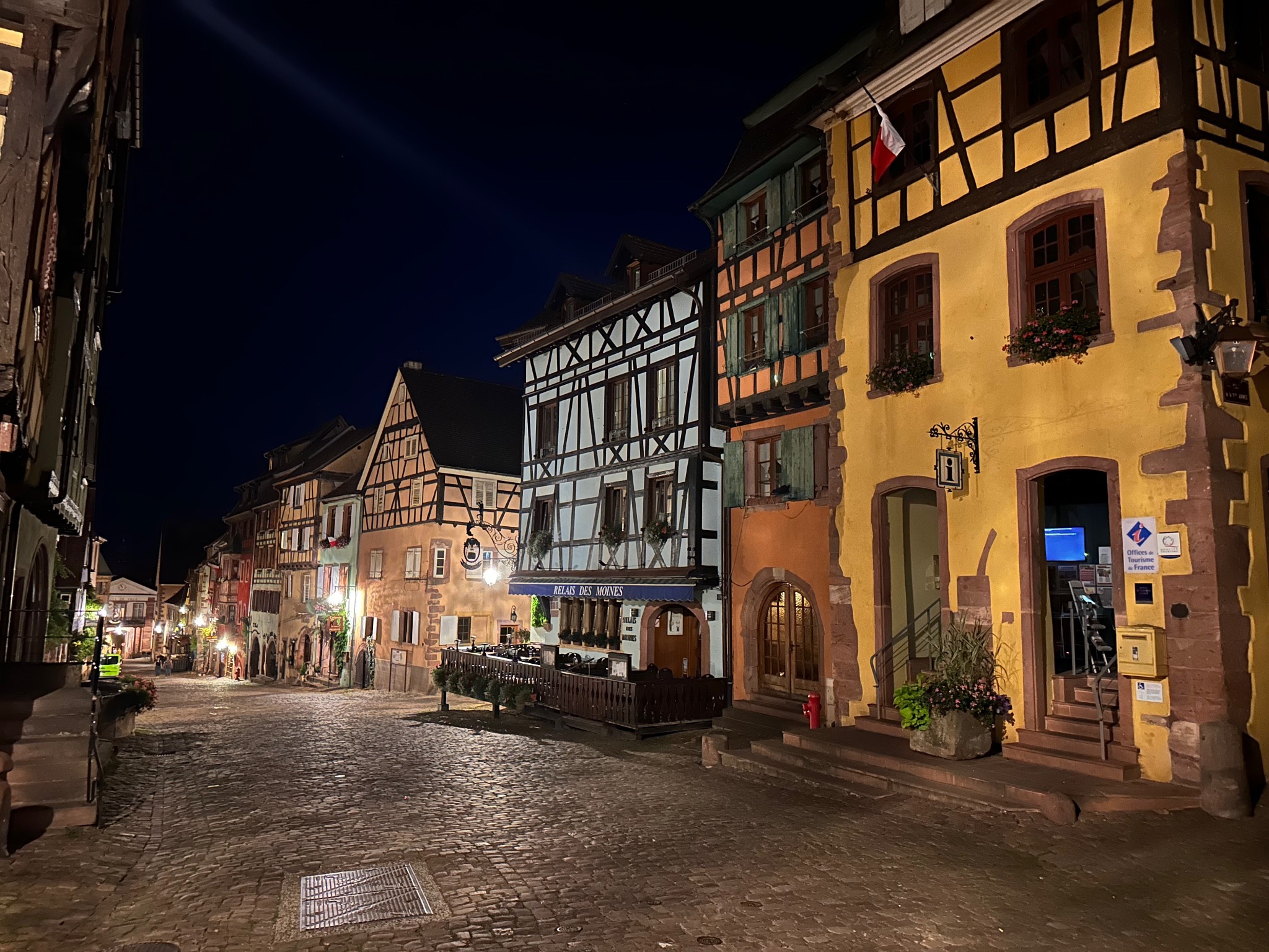 Une rue pavée bordée de maisons à colombages éclairées à la tombée de la nuit